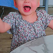 énaya a rejoint le concours — aidez-le/la à gagner de superbes lots ! toddler, child, happy, smiling, blue_eyes, floral_dress, table, marble_table, indoor, person, face, arms_raised, joy, young_child, cute, earrings, wooden_floor, chair, background, expression