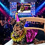 Pupuce participe au concours pour gagner de l'argent avec cette photo : animal, celebration, chair, colorful_lights, confetti, costume, decorations, dog, dog_clothing, event, festive, fun, indoor, party, party_hat, people, pet, projection, screen, smiling
