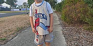 Cruze is registered to the contest to win money with this photo: child, boy, spiderman, cap, shorts, sneakers, sidewalk, outdoor, trees, grass, residential_area, smile, pose, street, daylight, casual_clothing, person, nature, happy, summer