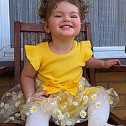 Mackenzie-Lee is registered to the contest to win money with this photo: child, toddler, smiling, yellow_dress, daisies, white_tights, wooden_chair, outdoor, happy, cute, portrait, sitting, playful, girl, clothing, window, background, hair, fun, dirt
