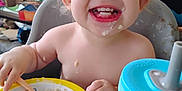 Maia joined the competition — help win amazing prizes! toddler, child, oatmeal, high_chair, food, smiling, face, messy, sippy_cup, table, spoon, kitchen, indoor, person, breakfast, baby_food, happy, meal, plastic_bowl, cute