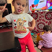 Jayla joined the competition — help win amazing prizes! child, toddler, baby, indoor, table, toy, television, carpet, clothing, person, play, furniture, pattern, red_pants, pink_socks, curly_hair, gesture, tongue_out, smile, living_room