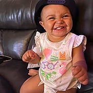 Jenesis joined the competition — help win amazing prizes! baby, cap, cartoon_print, child, clothing, couch, cute, diaper, face, feet, grinning, hand, happy, indoor, leather, person, shirt, sitting, skin, smile