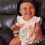 baby, cap, cartoon_print, child, clothing, couch, cute, diaper, face, feet, grinning, hand, happy, indoor, leather, person, shirt, sitting, skin, smile