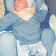 Nour participe au concours pour gagner de l'argent avec cette photo : baby, child, infant, gray_sweater, turban, bib, sheep_pattern, pants, cushioned_seat, blanket, cozy, indoor, soft_fabric, cute, comfort, relaxed, person, clothing, headwear, portrait