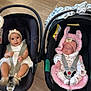 baby, infant, car_seat, child, sleeping, smiling, headband, pink, white_clothing, flooring, safety_harness, toy, newborn, cute, indoor, person, adorable, resting, carrying_handle, wood_floor