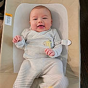 Zeke joined the competition — help win amazing prizes! baby, child, smiling, onesie, striped_clothing, giraffe_patch, cushion, beige, infant, happy, lying_down, footwear, kicking, indoor, cute, human, portrait, small_hands, soft_fabric, face