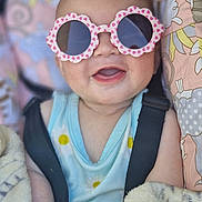 Adah-Jayne is registered to the contest to win money with this photo: baby, sunglasses, smile, blanket, seatbelt, child, infant, pastel, cute, clothing, happy, face, head, hand, comfort, pattern, pink, blue, soft, portrait