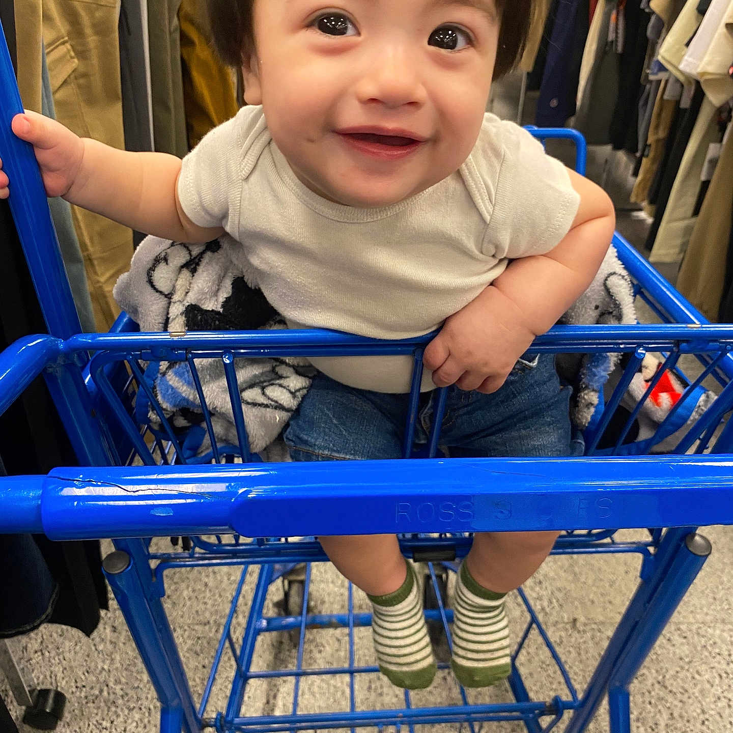 Zayden is registered to the contest to win money with this photo: apparel, baby, child, clothing, cute, floor, hand, happy, indoor, jeans, person, rack, retail, shopping, shopping_cart, smile, socks, store, toddler, white_shirt