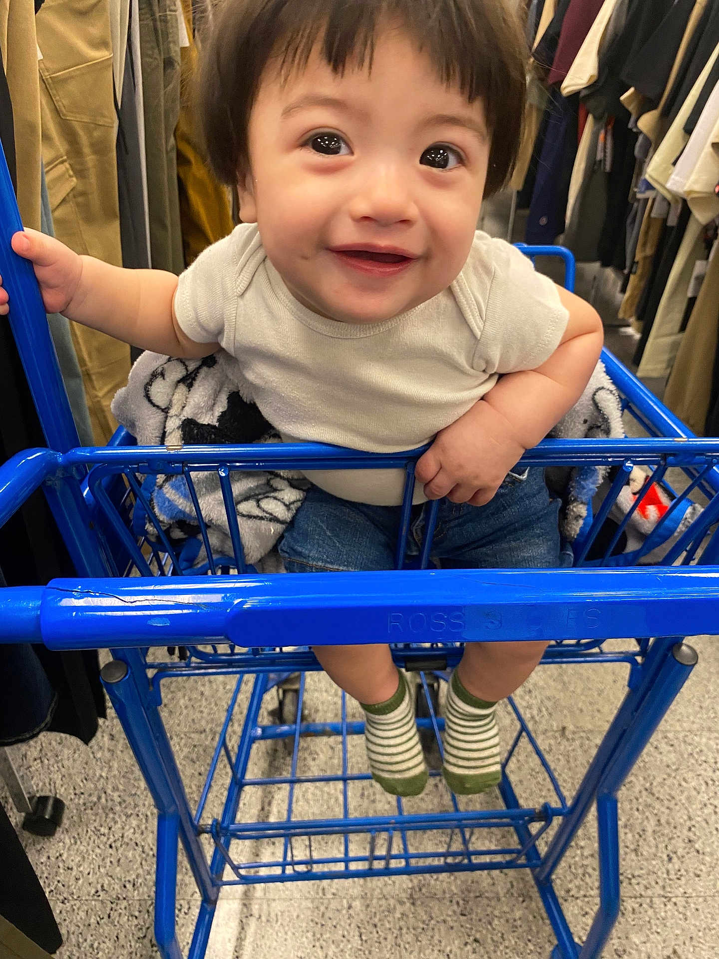 Zayden is registered to the contest to win money with this photo: toddler, child, shopping_cart, clothing, store, smile, cute, socks, jeans, white_shirt, hand, floor, retail, baby, rack, apparel, indoor, person, happy, shopping