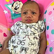 Leeana is registered to the contest to win money with this photo: baby, infant, face, tongue, expression, clothing, pattern, bows, mickey_mouse, minnie_mouse, pink, cushion, polka_dot, stars, heart, child, person, portrait, cute, indoor