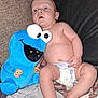 Jerald is registered to the contest to win money with this photo: baby, diaper, plush_toy, cookie_monster, couch, fabric, crumbs, blue, child, indoor, person, toy, expression, wide_eyes, skin, cute, sitting, comfort, soft, hand