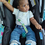 Damian is registered to the contest to win money with this photo: accessory, baby, black_hair, car_seat, casual_clothing, child, curious, cute, denim_jeans, footwear, indoor, infant, pacifier, person, portrait, seat_belt, sneakers, suspenders, toddler, white_shirt