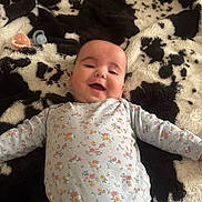 Ella Mae is registered to the contest to win money with this photo: baby, smiling, onesie, floral, pacifier, blanket, black_and_white, infant, face, happy, child, cute, lying_down, soft, patterned, cozy, comfort, baby_girl, indoors, portrait