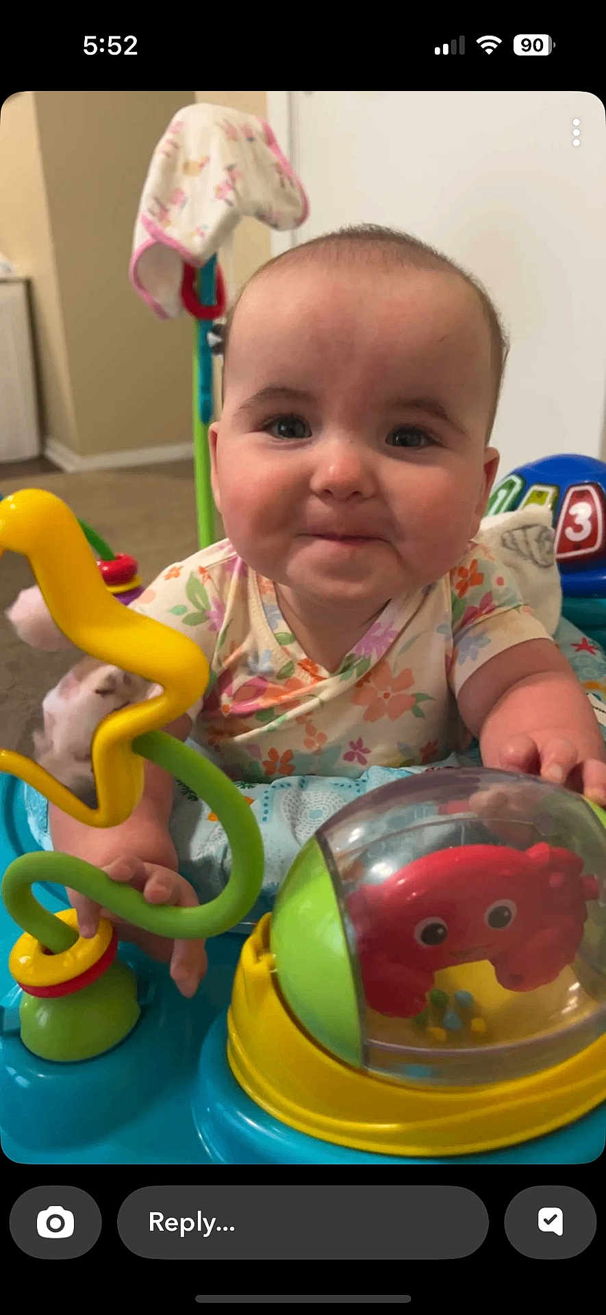 Ella Mae is registered to the contest to win money with this photo: baby, child, toy, activity_center, indoor, play, colorful, rattle, crab_toy, onesie, floral_pattern, smile, face, hands, floor, carpet, background, furniture, playtime, happy