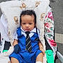 Elyôn participe au concours pour gagner de l'argent avec cette photo : baby, baby_accessory, blanket, blue_outfit, child, clothing, curly_hair, cute, infant, lion_print, outdoor, pavement, person, portrait, road, socks, stroller, tie, urban, young_child