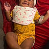 Essence is registered to the contest to win money with this photo: baby, smiling, headband, bib, red_blanket, yellow_onesie, infant, happy, lying_down, foot, hand, cute, playful, cozy, indoors, child, person, skin, fabric, blanket