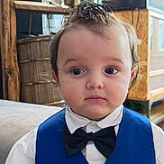 Noah participe au concours pour gagner de l'argent avec cette photo : child, toddler, boy, formal_wear, bow_tie, vest, white_shirt, indoors, furniture, curious_expression, hairstyle, portrait, young_child, cute, person, face, eyes, sitting, clothing, home
