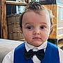 child, toddler, boy, formal_wear, bow_tie, vest, white_shirt, indoors, furniture, curious_expression, hairstyle, portrait, young_child, cute, person, face, eyes, sitting, clothing, home