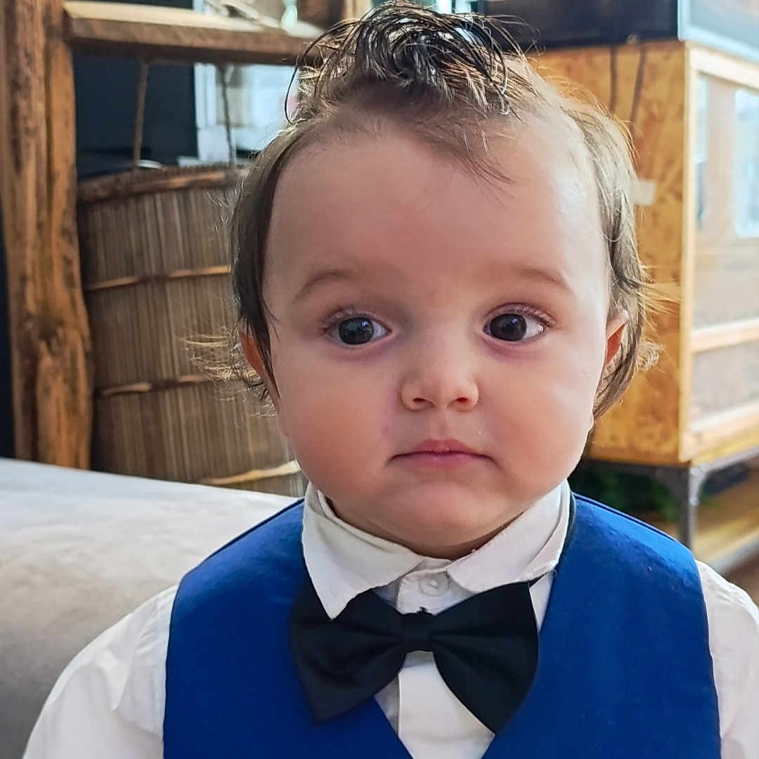 Noah participe au concours pour gagner de l'argent avec cette photo : bow_tie, boy, child, clothing, curious_expression, cute, eyes, face, formal_wear, furniture, hairstyle, home, indoors, person, portrait, sitting, toddler, vest, white_shirt, young_child
