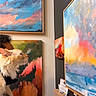 cat, person, art_gallery, painting, abstract_art, colorful, shoulder, indoor, animal, curious, cream_colored_cat, human, contemplation, art_exhibit, decor, canvas, expression, gallery_wall, head, animal_companion