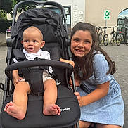 Maïssa a rejoint le concours — aidez-le/la à gagner de superbes lots ! baby, bicycle, casual, child, clothing, curious, daylight, family, footwear, girl, happy, outdoor, park, pavement, person, smile, stroller, toddler, tree, urban