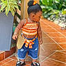 Jazlynn is registered to the contest to win money with this photo: child, toddler, girl, portrait, outdoor, patio, plants, tropical, fashion, orange_bow, hairstyle, jewelry, necklace, purse, denim_shorts, sandals, smiling, standing, tile_floor, garden