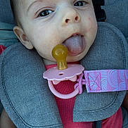 Sage is registered to the contest to win money with this photo: baby, infant, pacifier, tongue, car_seat, seatbelt, harness, pink_clothing, close_up, child, face, cute, playful, young_child, safety, seat, child_seat, expression, person, baby_girl