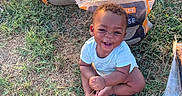 Emmanuel joined the competition — help win amazing prizes! baby, child, infant, smiling, happy, sitting, outdoor, grass, garden, gardening, soil_bags, potting_mix, garden_tool, barefoot, portrait, face, curly_hair, blue_shirt, sunlight, lawn