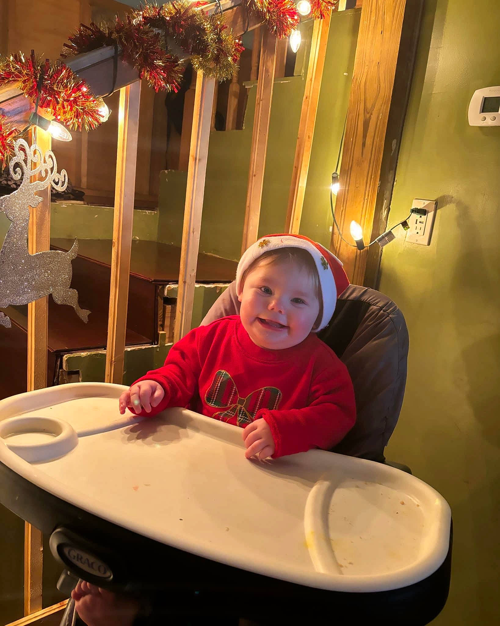 Deanna joined the competition — help win amazing prizes! chair, christmas, christmas_decoration, christmas_ornament, design, event, fun, happy, holiday, holiday_ornament, joy, leisure, light, ornament, person, room, sitting, smile, table, toddler