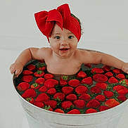 Peyton joined the competition — help win amazing prizes! baby, child, red_bow, headband, strawberries, metal_tub, water, happy, smiling, cute, infant, fruit, bath, playful, indoors, skin, arms, sitting, fresh, fun