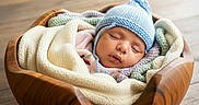 Rabab is registered to the contest to win money with this photo: baby, baby_clothing, blanket, celebration, child, cozy, cute, headwear, indoor, infant, knit_hat, milestone, newborn, peaceful, portrait, sleeping, soft_lighting, wooden_bowl, wooden_table, wrapped
