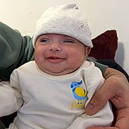 Rabab joined the competition — help win amazing prizes! baby, smiling, infant, hat, white_clothing, hand, adult, cozy, cute, happy, indoors, person, portrait, child, warm, casual, sitting, face, young, comfort