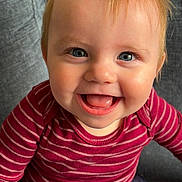 Connor is registered to the contest to win money with this photo: baby, blue_eyes, chair, child, close_up, cozy, face, happy, indoor, infant, laughing, open_mouth, photography, portrait, red_clothing, red_hair, seated, smiling, striped_shirt, teeth
