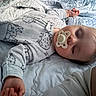 baby, sleeping, pacifier, infant, bed, blanket, quilt, pajamas, clothing, portrait, indoors, cozy, resting, face, closed_eyes, hand, arm, soft_lighting, nursery, peaceful
