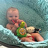 Connor is registered to the contest to win money with this photo: baby, child, infant, smiling, sitting, portrait, toy, teething_ring, musical_toy, stuffed_animal, green_toy, fluffy_blanket, aqua, indoor, carpet, playseat, nursery, happy, face, photography
