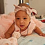 baby, bed, blanket, bow, child, comfort, cute, expression, face, headband, indoors, infant, necklace, person, pink_dress, room, sleepwear, soft_lighting, tummy_time, young_child