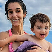 Elijah joined the competition — help win amazing prizes! woman, child, toddler, smile, happy, holding, towel, outdoor, sky, clouds, portrait, people, hair, skin, expression, summer, daylight, bare_shoulders, closeup, family