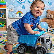 Atreus is registered to the contest to win money with this photo: balloon, banner, blue_shirt, carpet, child, clouds, colorful_rings, happy, indoor, playing, playroom, rainbow_toy, shorts, smiling, sneakers, stars, stuffed_animals, teddy_bear, toddler, toy_truck