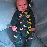 Kade Atticus is registered to the contest to win money with this photo: baby, infant, onesie, dinosaur_costume, spikes, blue_couch, soft_furniture, cute, child, sitting, indoors, comfortable, curious, clothing, footwear_absent, portrait, young, skin, face, hand