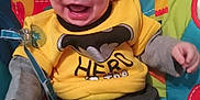 Kade Atticus is registered to the contest to win money with this photo: baby, smiling, yellow_shirt, pants, baby_seat, colorful, happy, child, indoors, cute, infant, face, clothing, person, sitting, joyful, expression, young_child, fun, casual