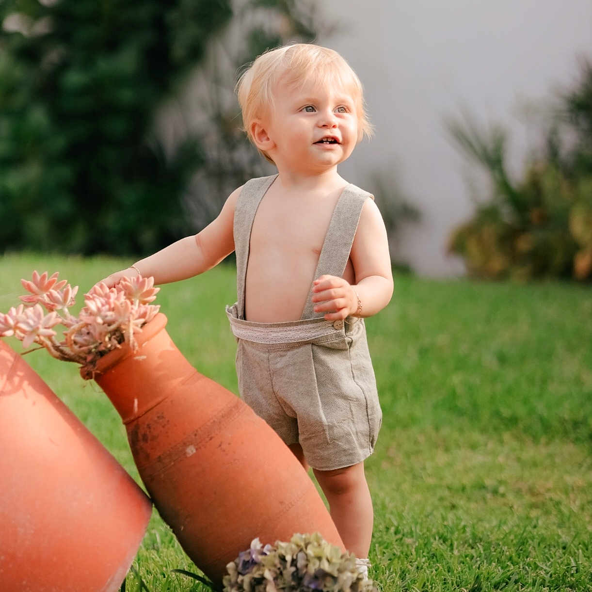 Lorenzo participe au concours pour gagner de l'argent avec cette photo : barefoot, blonde_hair, child, curious, daylight, flower, garden, grass, greenery, nature, outdoor, plants, portrait, smiling, succulent, sunlight, suspenders, terracotta_pot, toddler, young_child