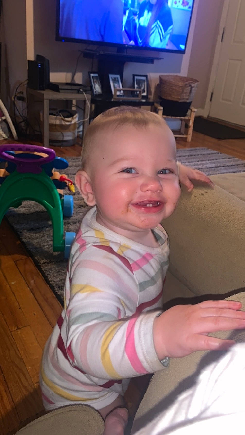 Harper is registered to the contest to win money with this photo: baby, baby_toddler_clothing, chair, cheek, child, eye, finger, floor, flooring, fun, furniture, happy, head, iris, joy, person, skin, smile, table, television