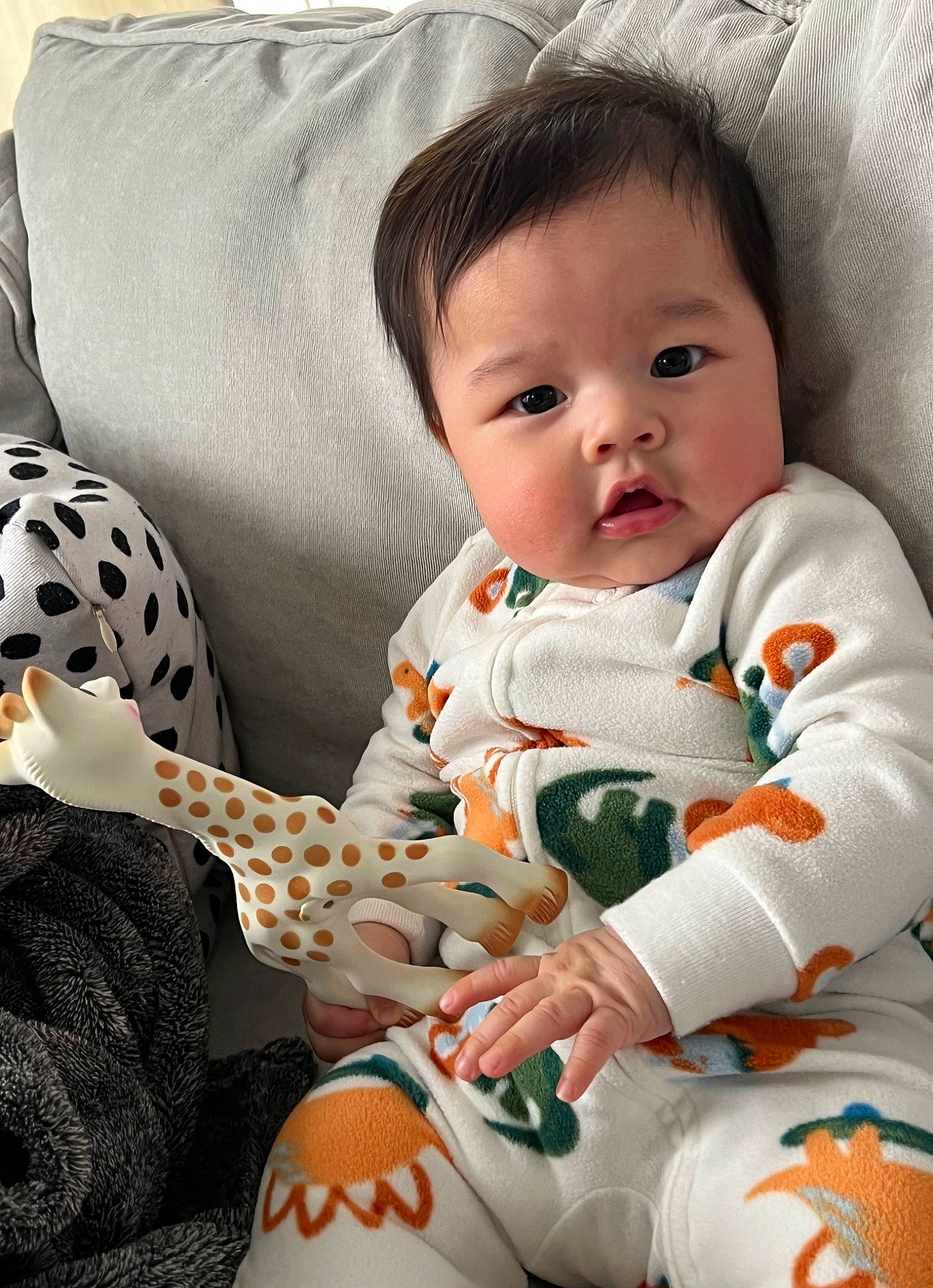 Enzo is registered to the contest to win money with this photo: baby, baby_toddler_clothing, cheek, child, comfort, face, facial_expression, happy, lap, linens, orange, pattern, person, pillow, product, sitting, sleeve, sock, t_shirt, textile