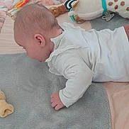 Chloé a rejoint le concours — aidez-le/la à gagner de superbes lots ! baby, infant, toy, blanket, plush_toy, bed, crib, sleepwear, child, tummy_time, soft_texture, cute, indoors, person, young_child, cozy, stuffed_animal, white_clothing, brown_pants, nursery