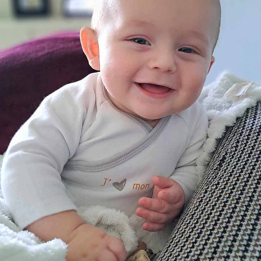 Noë-Jules participe au concours pour gagner de l'argent avec cette photo : applique, baby, babylaughing, blanket, bodypart, couch, face, finger, furniture, hand, happy, head, laughing, newborn, person, photography, portrait, quilt, sitting, smile