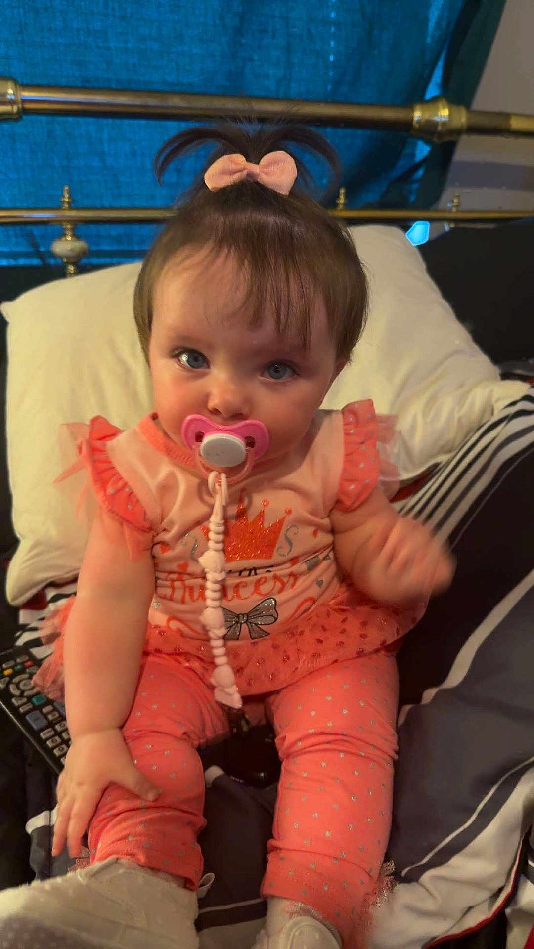 Lilyonna joined the competition — help win amazing prizes! baby, child, pacifier, pink_bow, princess_outfit, sitting, bed, pillow, remote_control, leggings, cute, infant, clothing, indoor, person, white_shoes, toddler, curious, hair_tie, plush