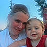 Josh is registered to the contest to win money with this photo: child, toddler, adult, parent, selfie, portrait, smiling, outdoor, family, affection, red_shirt, white_shirt, blue_sky, trees, background_person, photobomb, close_up, face, daylight, utility_wires