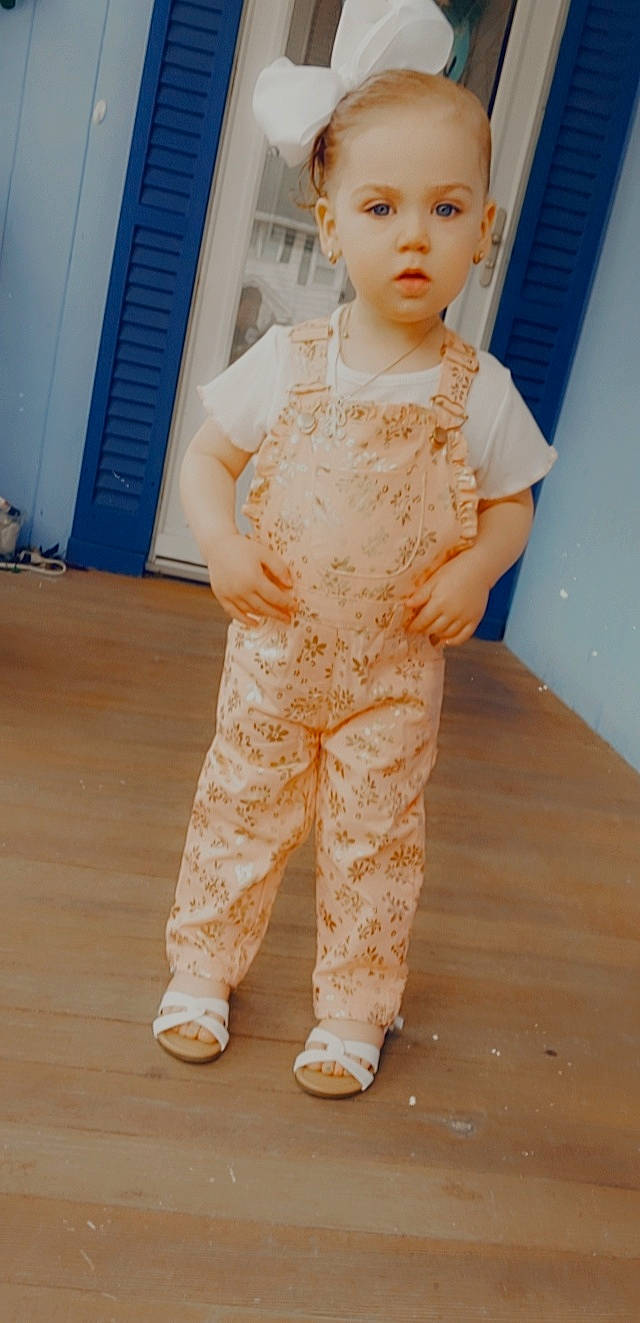 Maddelynn is registered to the contest to win money with this photo: baby_toddler_clothing, blue, child, dress, fashion_design, floor, flooring, formal_wear, hardwood, human_leg, neck, one_piece_garment, pattern, peach, person, sleeve, standing, toy, trunk, waist