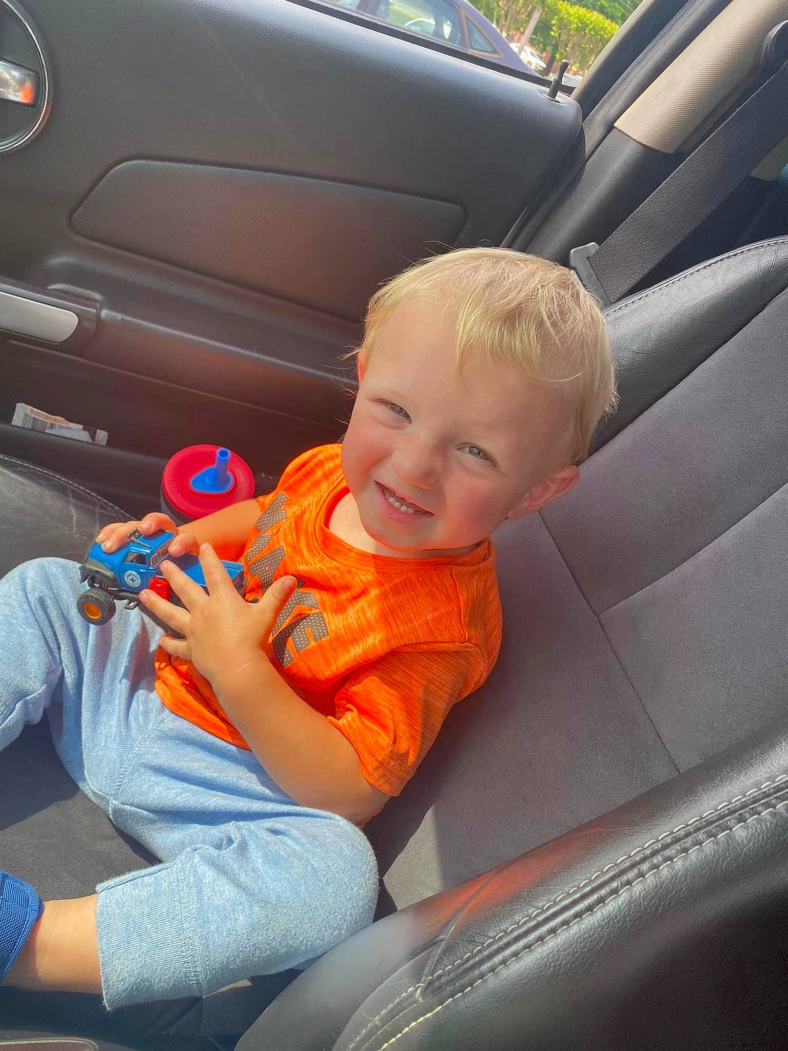 Liam joined the competition — help win amazing prizes! auto_part, automotive_design, automotive_exterior, automotive_lighting, car, car_seat, car_seat_cover, mode_of_transport, motor_vehicle, orange, person, personal_luxury_car, plant, product, smile, steering_part, steering_wheel, tints_and_shades, toddler, vehicle